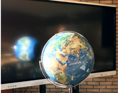 ein Globus vor einem ausgeschalteten Smartboard