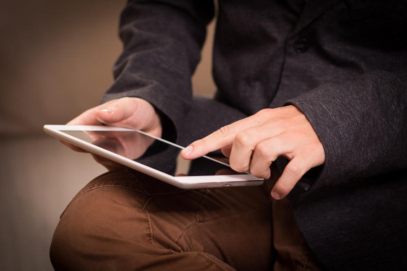 Eine Person hält ein Tablet auf dem Schoß.